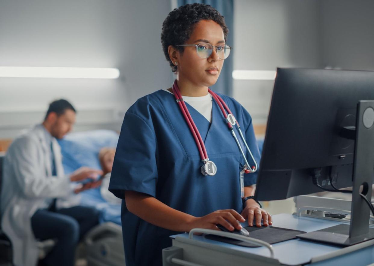 Acute care nurse at terminal in hospital room. -