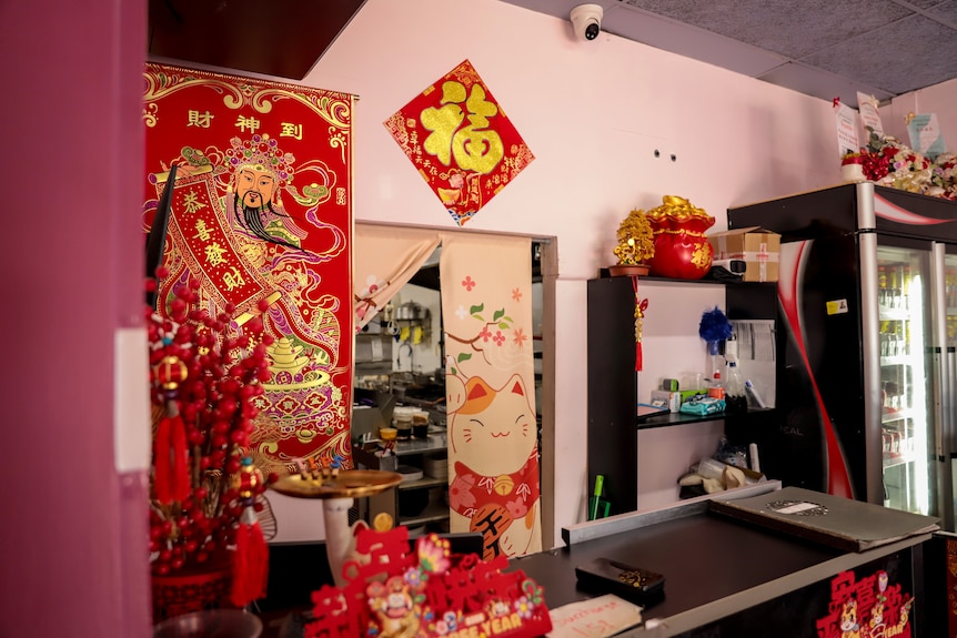 The interior of a Chinese restaurant with red and gold decorations behind a serving counter