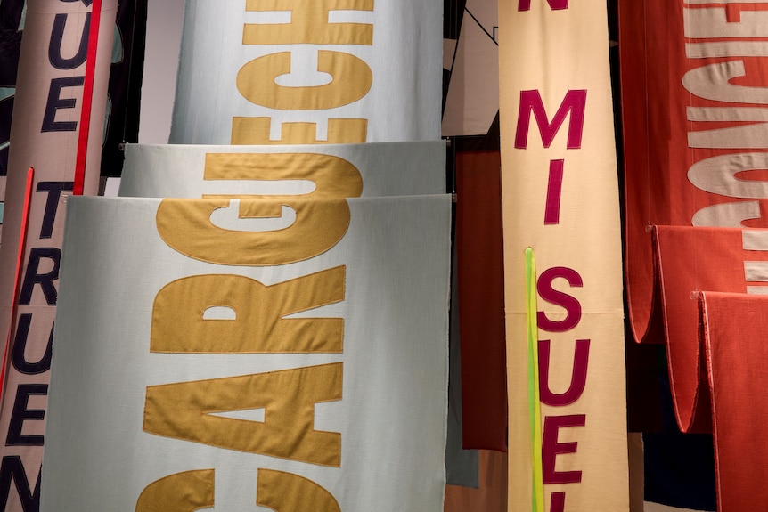 A close-up of textile banners emblazoned with text featured in Nadia Hernandez's installation at AGNSW.