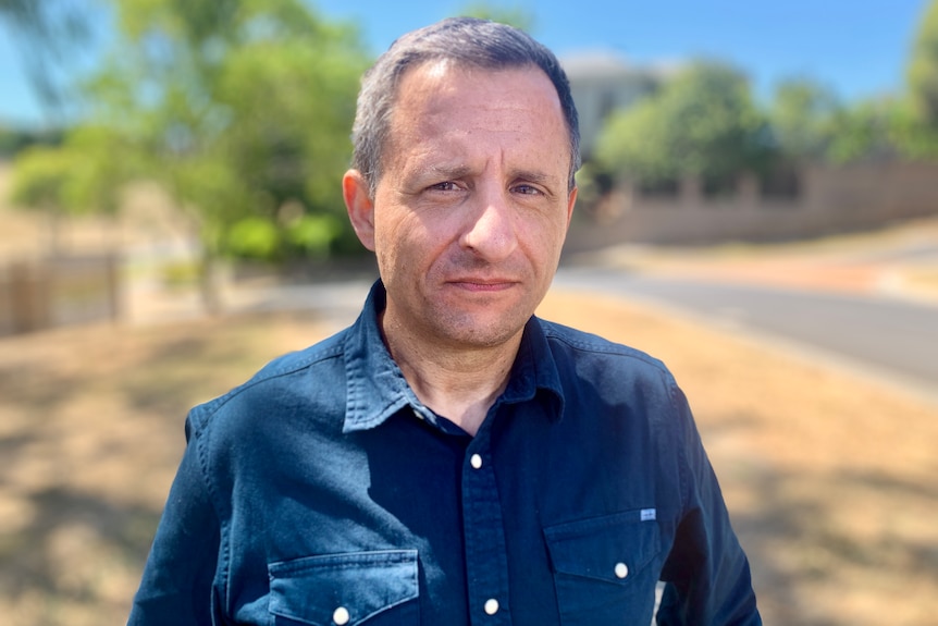 Man standing on a suburban Melbourne street in a blue shirt