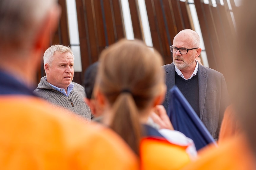 Two mean speaking to workers at a press conference