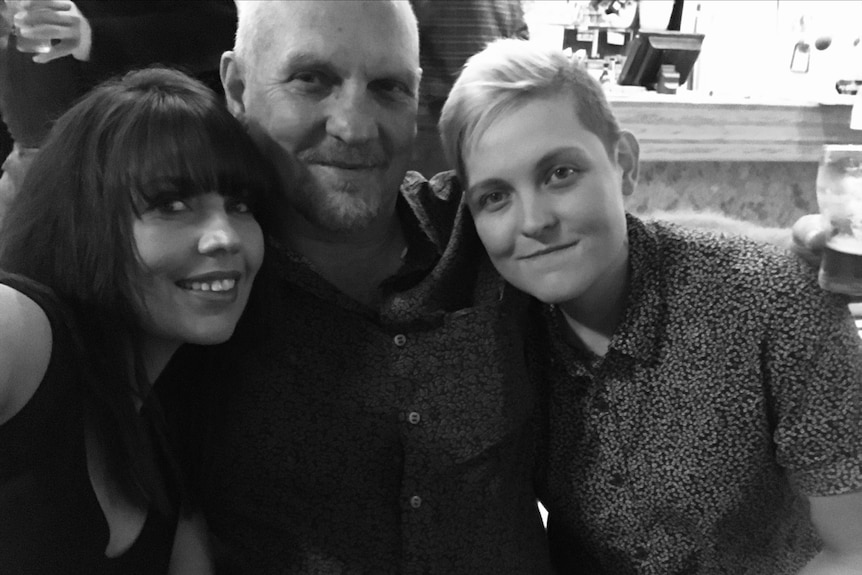 black and white image of two women with man in the middle, all smiling