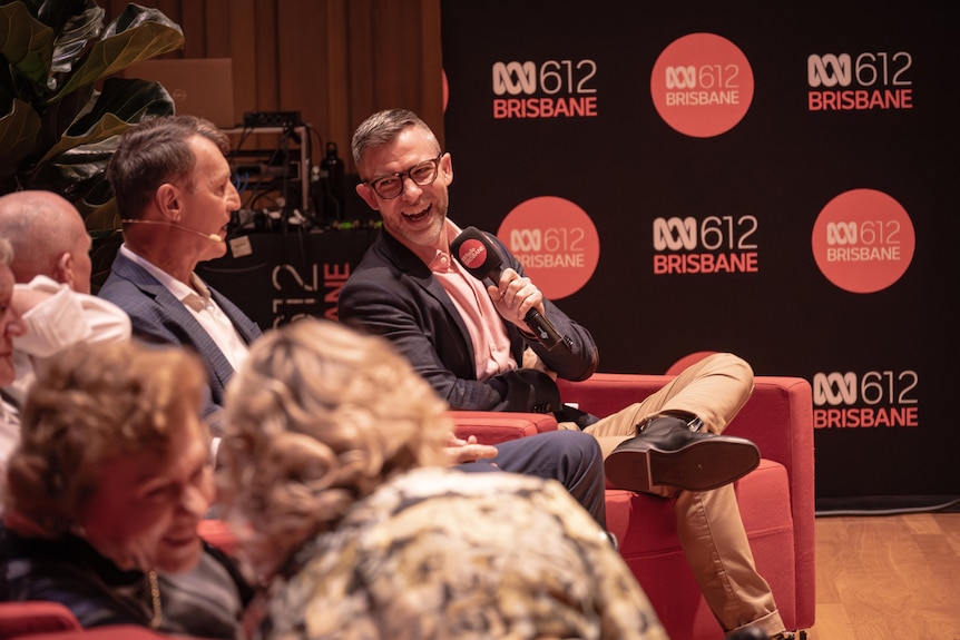 A man with a microphone smiling on a panel