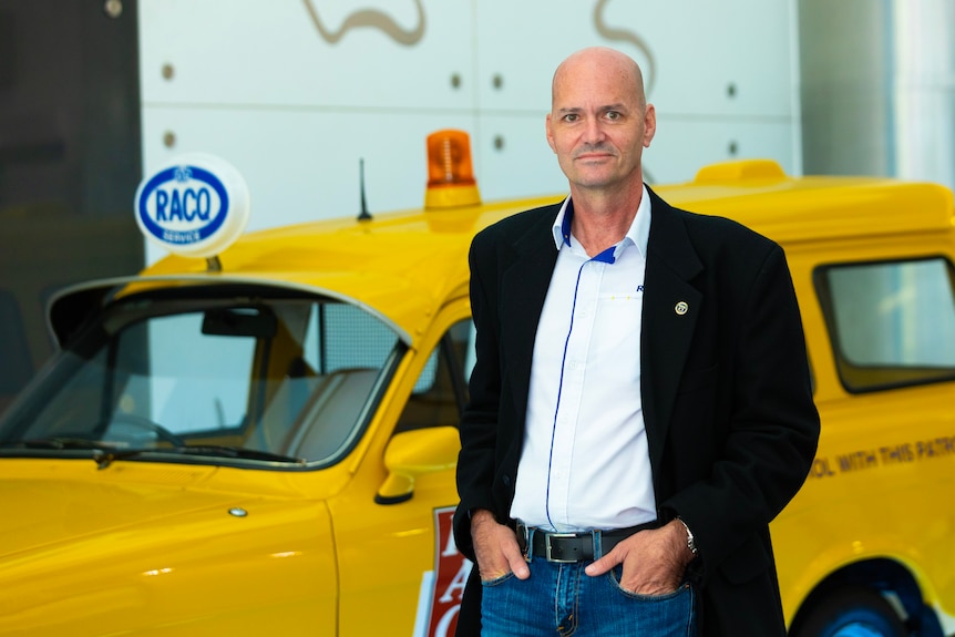 Man in suit standing beside yellow vehicle