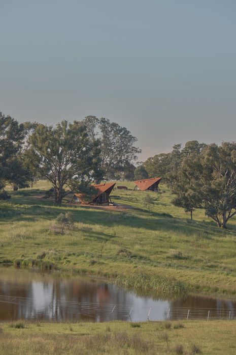 Two sharply profiled A-frame steel cabins sit lightly within the undulating landscape outside Orange, NSW.
