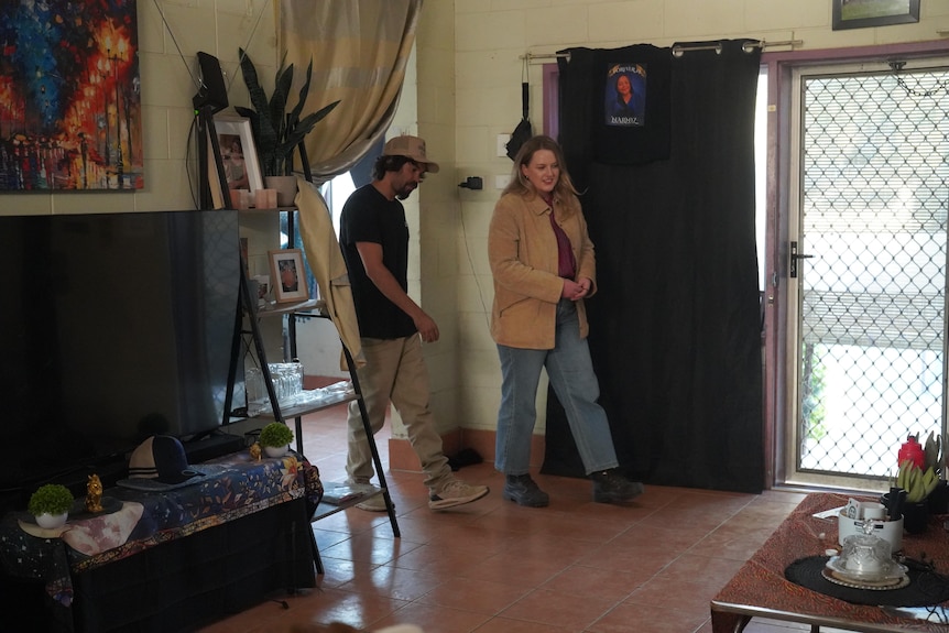 Harley Pompey-Myers and Dana Morse walk into a tiled lounge room.