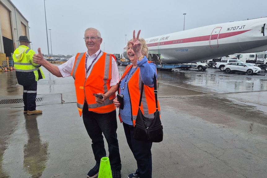 Bob and Maureen celebrate in front of the aircraft wearing high vis vests.
