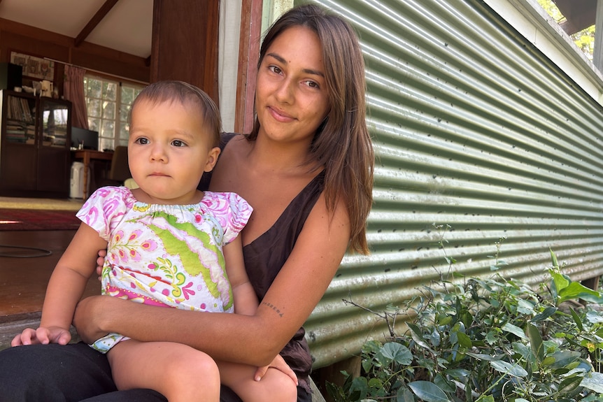 A women with long brown hair and a child sitting on her lap