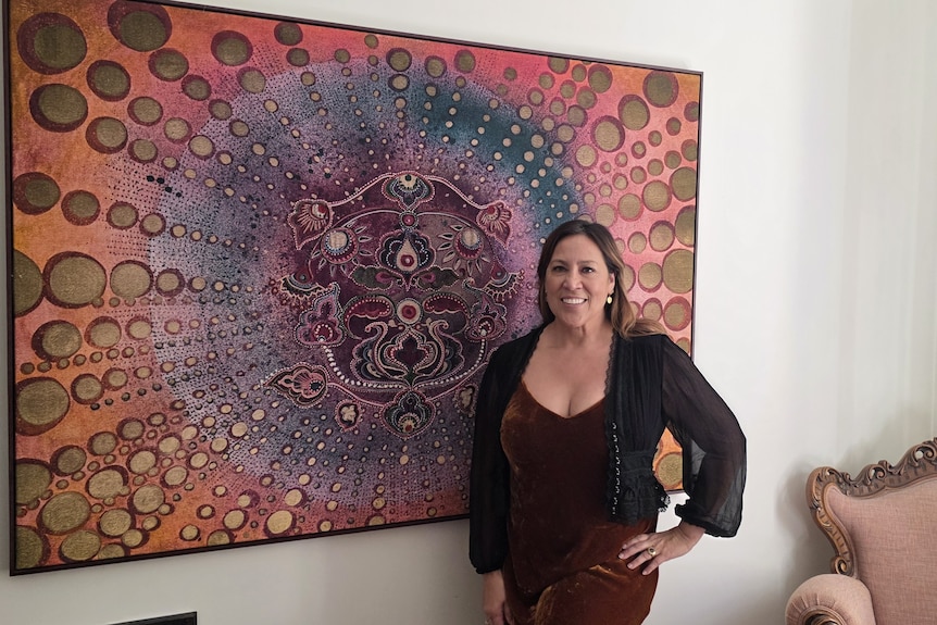 Lady standing in front of a painting on the wall.
