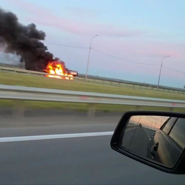 A large amount of flames and smoke, seen from the window of a nearby car.