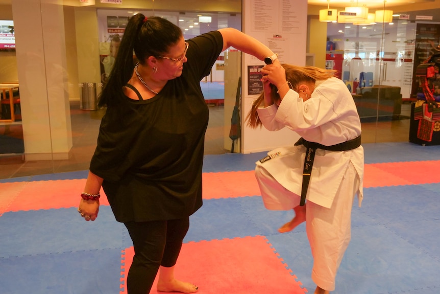Two women practise karate on mats