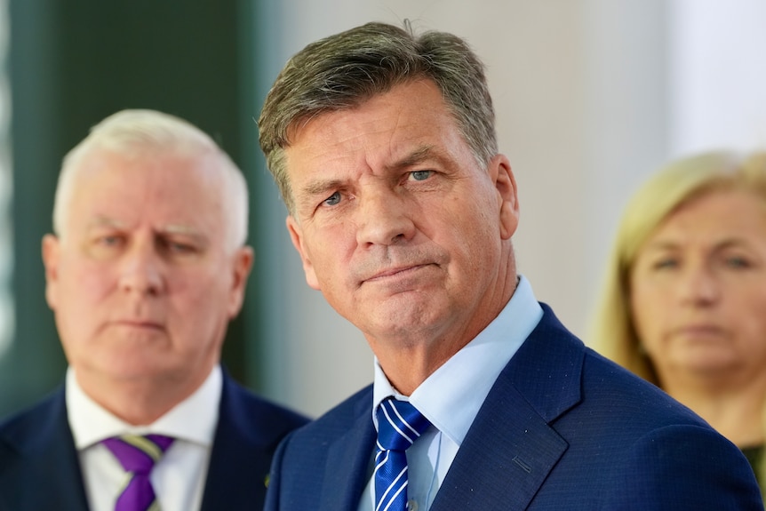 Two men and a woman wearing suits.