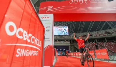 A cyclist raising his arms in celebration as he crosses the OCBC Cycle finishing line at The Kallang on May 10, 2026.
