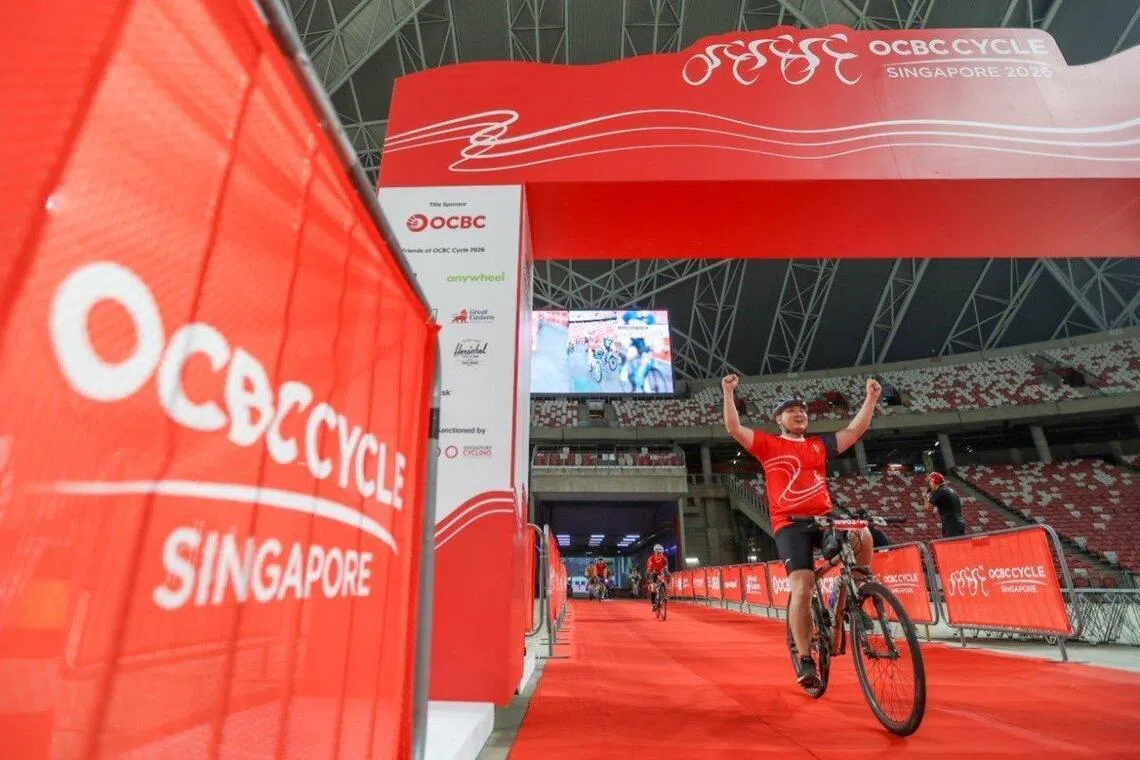 A cyclist raising his arms in celebration as he crosses the OCBC Cycle finishing line at The Kallang on May 10, 2026.