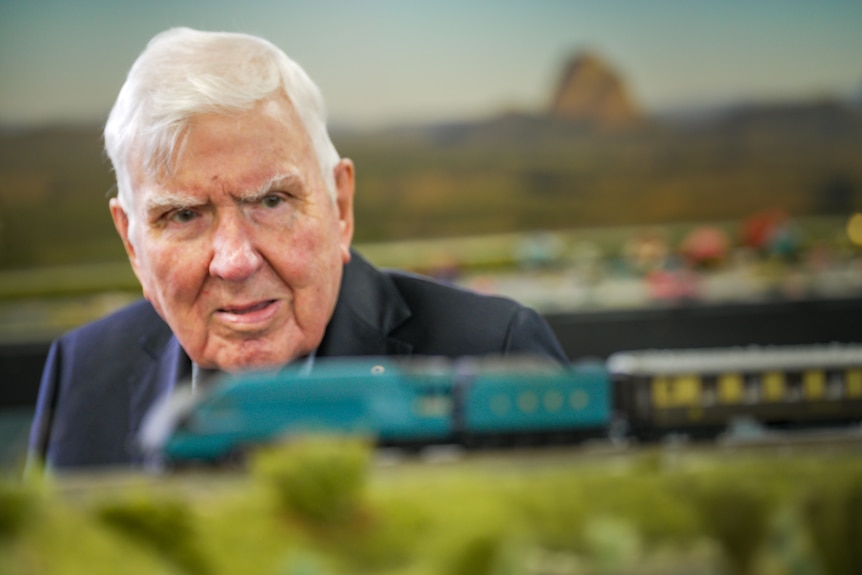 Old man looking at model train.
