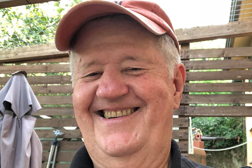 A smiling man wearing a baseball cap