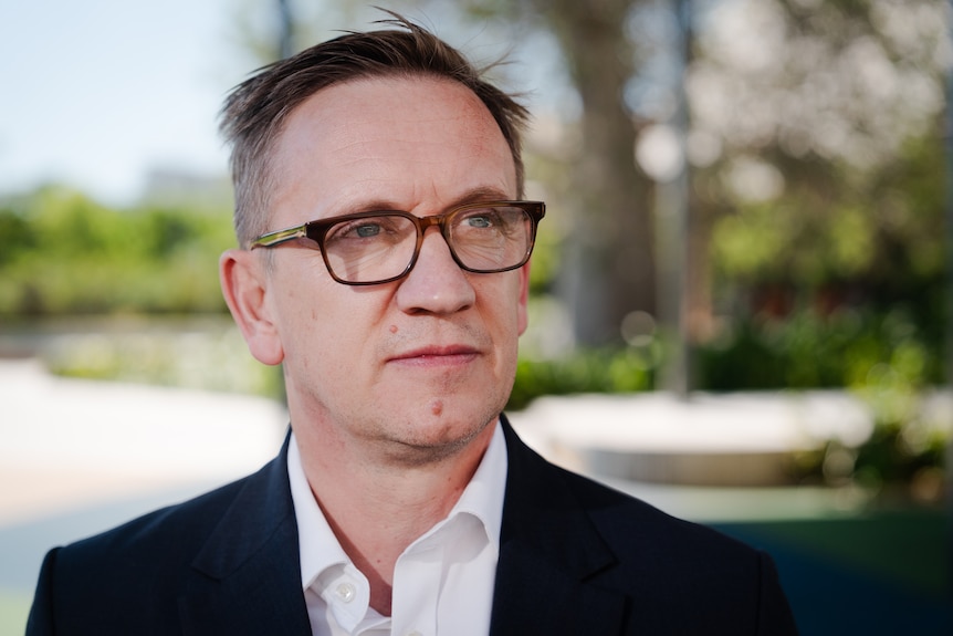 A man in glasses and suit looking slightly off camera