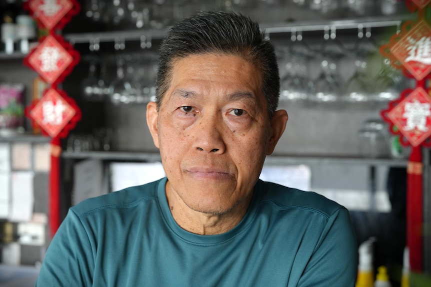 A man in a grey shirt with dark hair