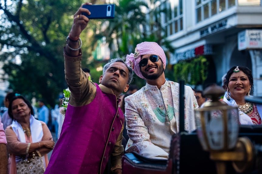 A man takes a selfie with the groom.