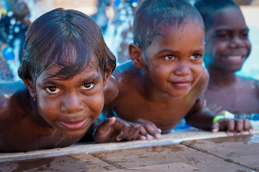 A trio of young Aboriginal boys climb out of a public pool.