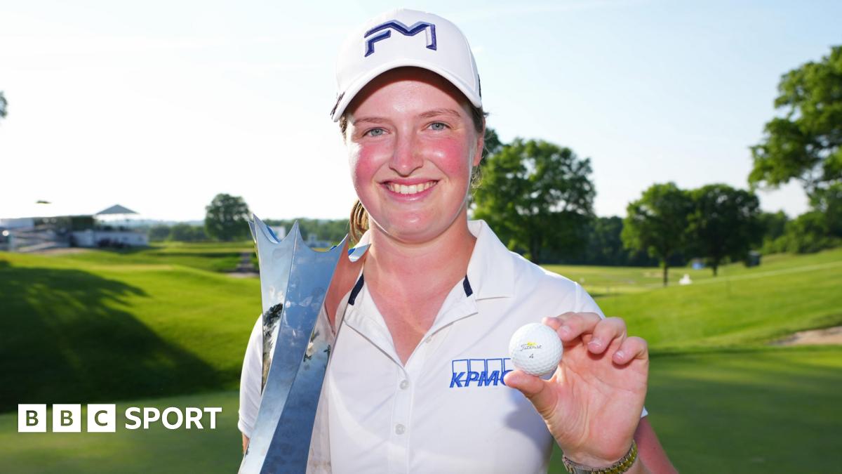 Lottie Woad smiling and holding a trophy and a golf ball