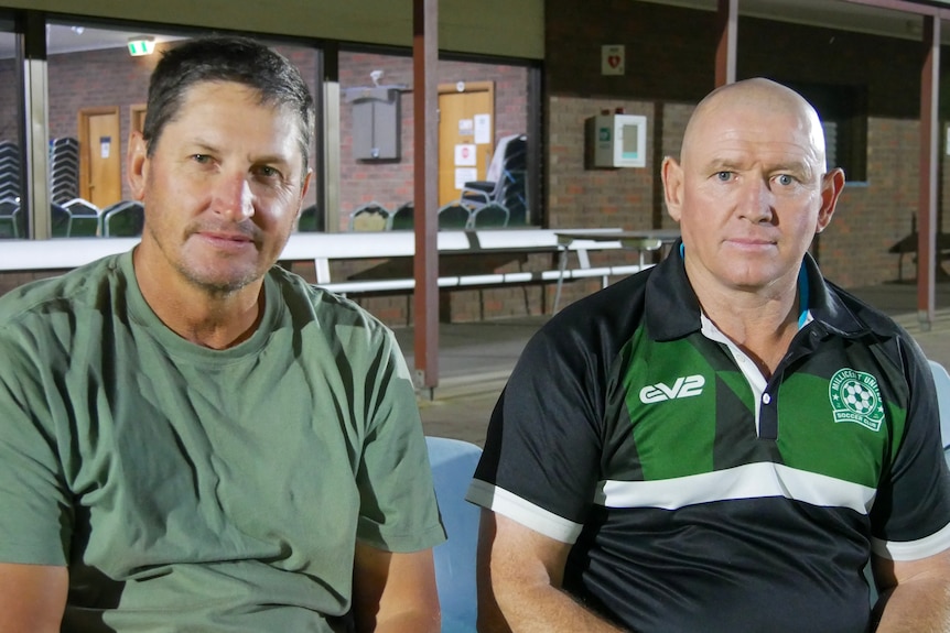 Two men sitting on seats next to each other.