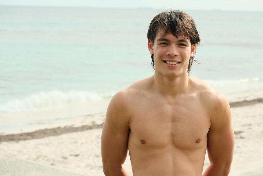 A topless young male at the beach. 