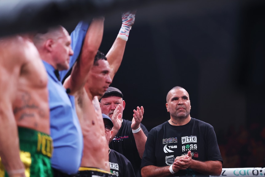 Anthony Mundine watches from the side as the ref raises his son Rahim's arm