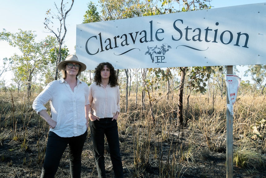 Two women look serious in front of a sign at Claravale Station. 