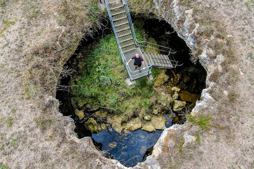 An aerial view of a man on a platform to a cave in South Australia.