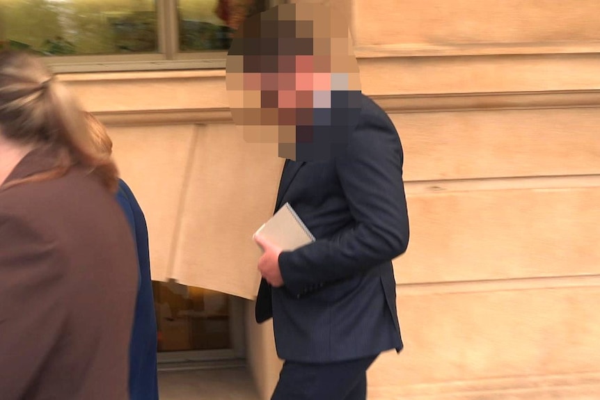 A person with a blurred face outside court.