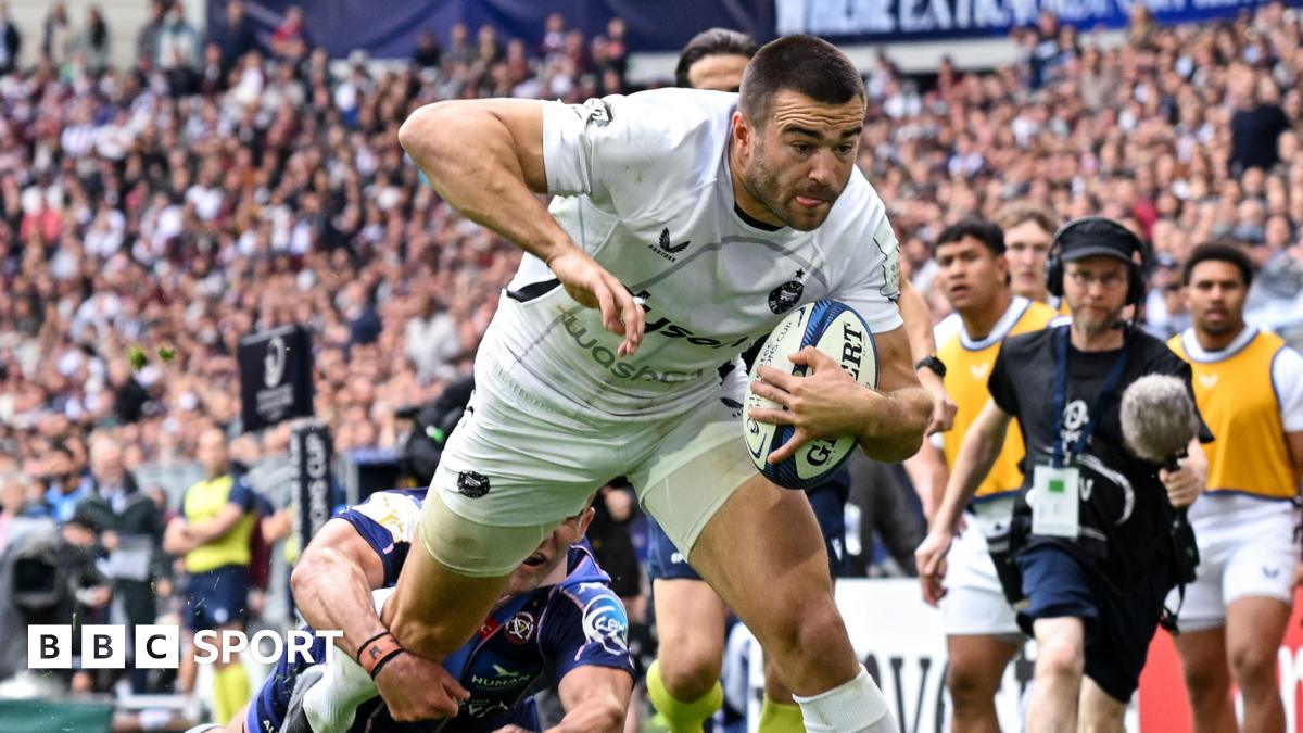 Will Muir dives towards the line with the ball under his left arm as a Bordeaux player wraps his arm around his right leg in an attempt to prevent a try during their Champions Cup match