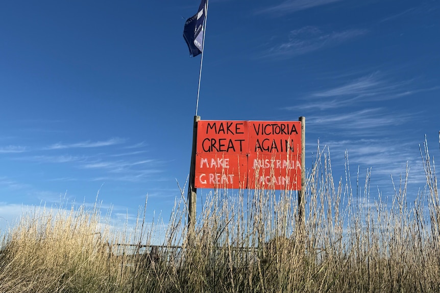 A sign reading "Make Australia Great Again" sits against a fence next to a Eureka flag