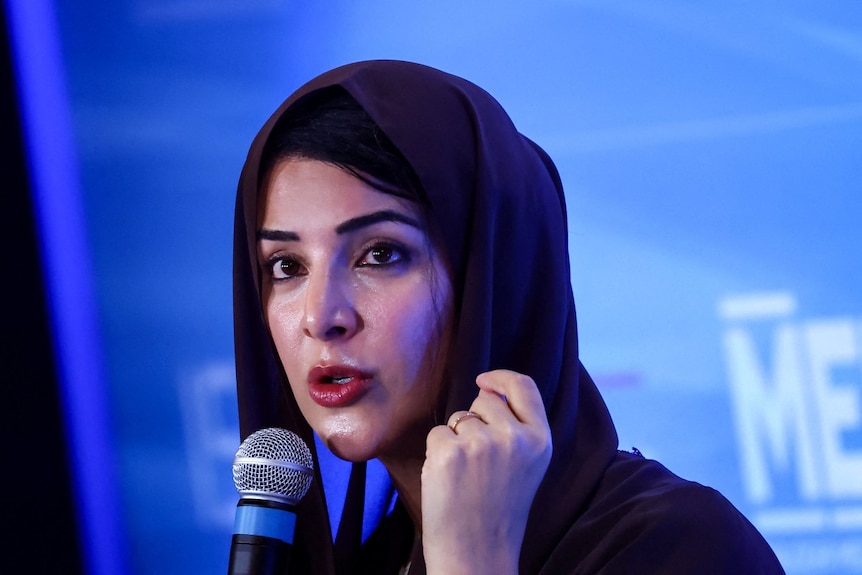 A woman speaking in to a microphone and looking on
