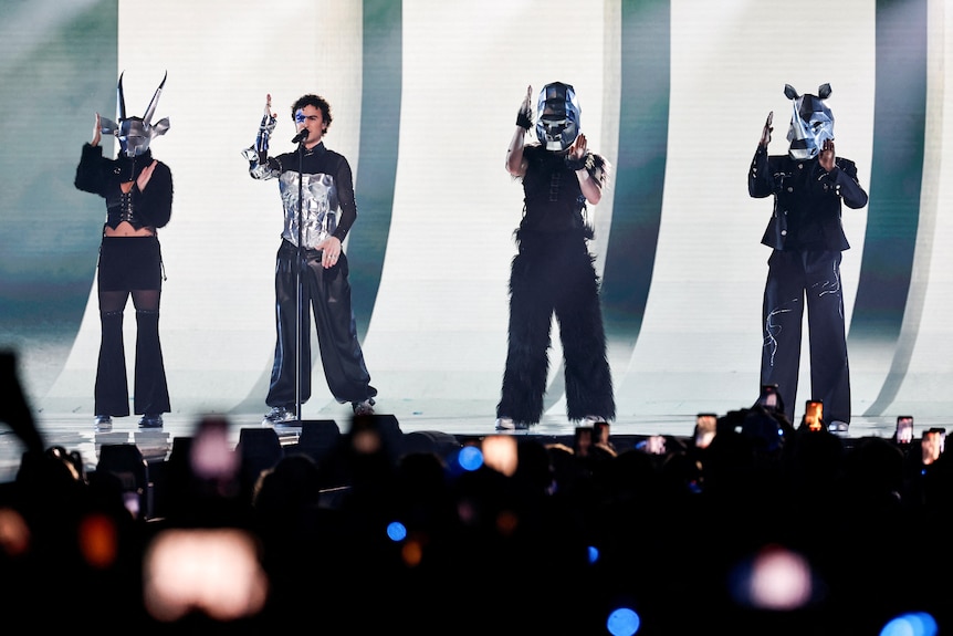 Cosmo, alongside his dancers wearing silver animal masks, dance onstage