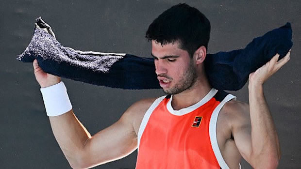 Carlos Alcaraz of Spain tries to stay cool with a wet towel alongside his team.