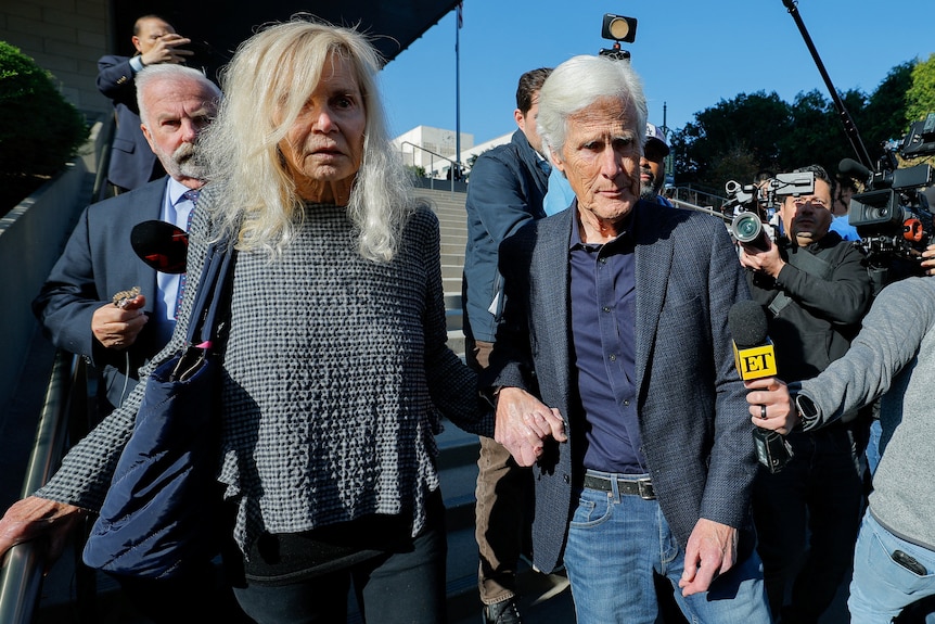 Suzanne Perry and Keith Morrison walking surrounded by microphones.