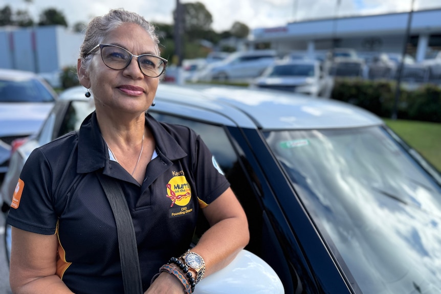 Smiling woman beside car in uniform