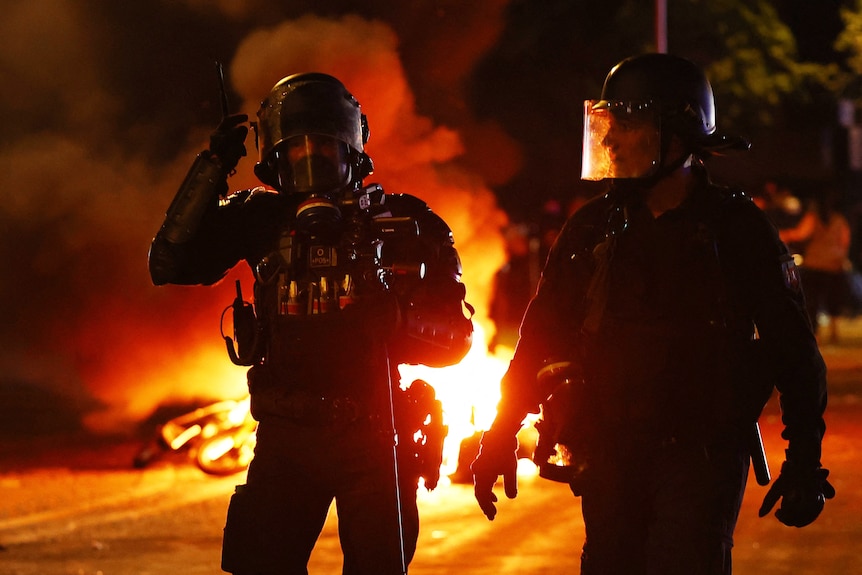 Police are silhouetted in front of a fire on Paris streets.