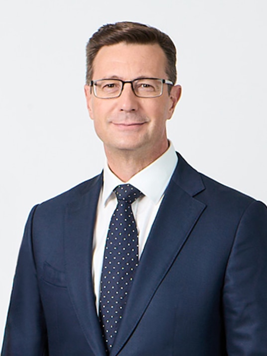 A head shot of a smiling Peter in a suit.