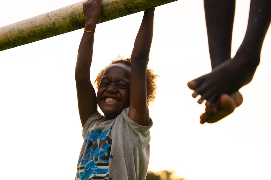 Children playing on a pole in the town of Buka are all smiles on a sunny afternoon.