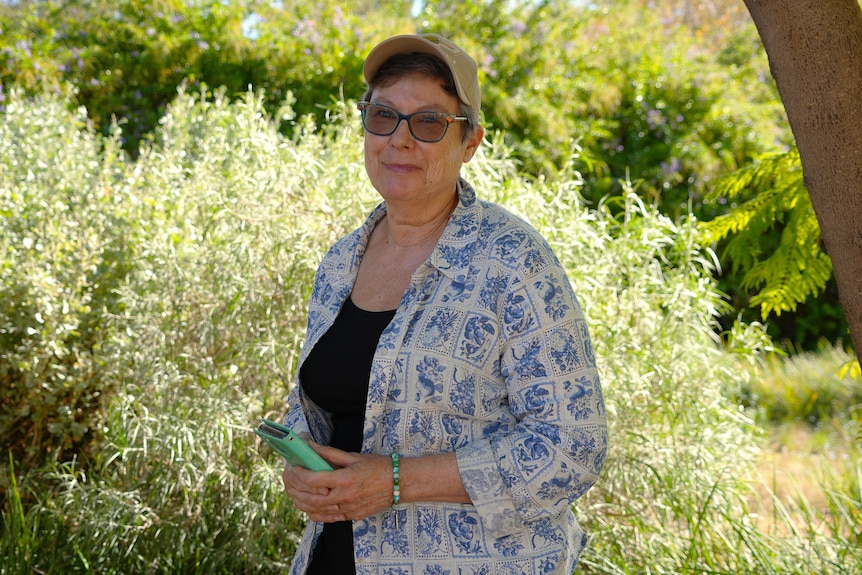 A woman standing in her backyard smiling