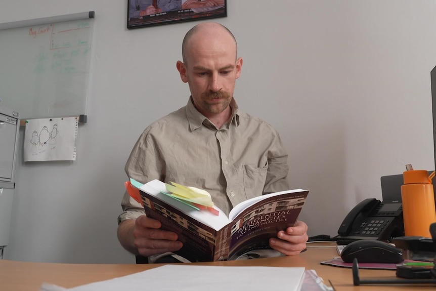 A man reads a law book at a desk.