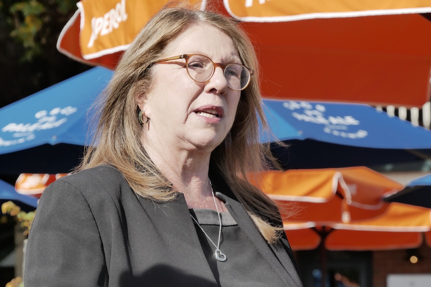 A middle-aged woman in glasses and a blazer.
