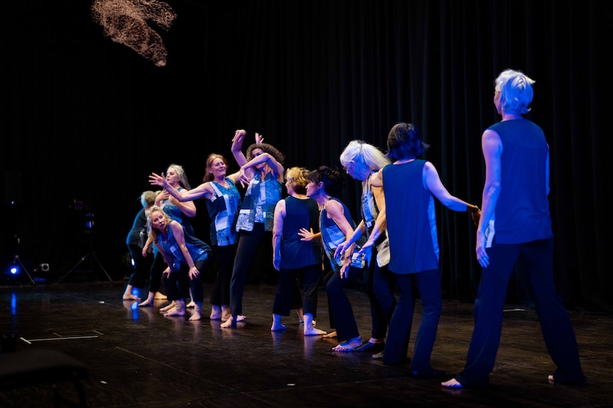 Mature-aged women doing dance practise in a studio with blue light