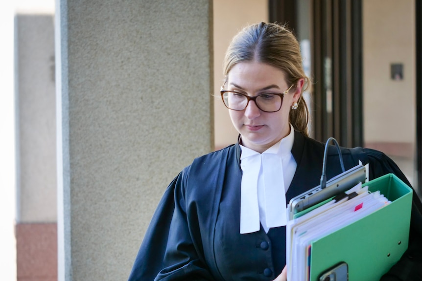 A female barrister in robes holding a green binder