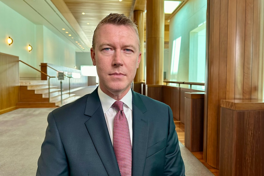 Man wearing a suit with a maroon tie.