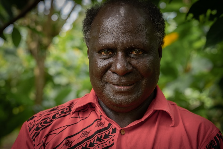 A close up photo of Albert in a red shirt and smiling at the camera.