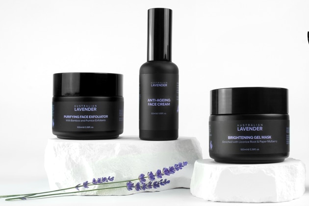 Four skin care products are being displayed against a black background, all black packaging.