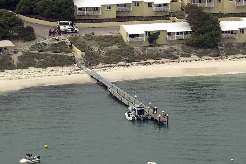 Police and ambulance parked near a jetty at a bay